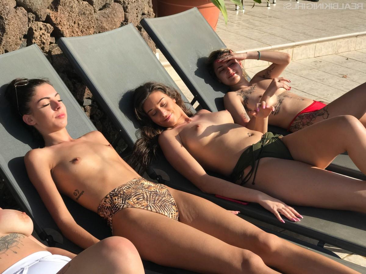 15P Vier Mädchen ziehen beim Sonnenbaden auf Liegestühlen ihre Bikinioberteile aus
