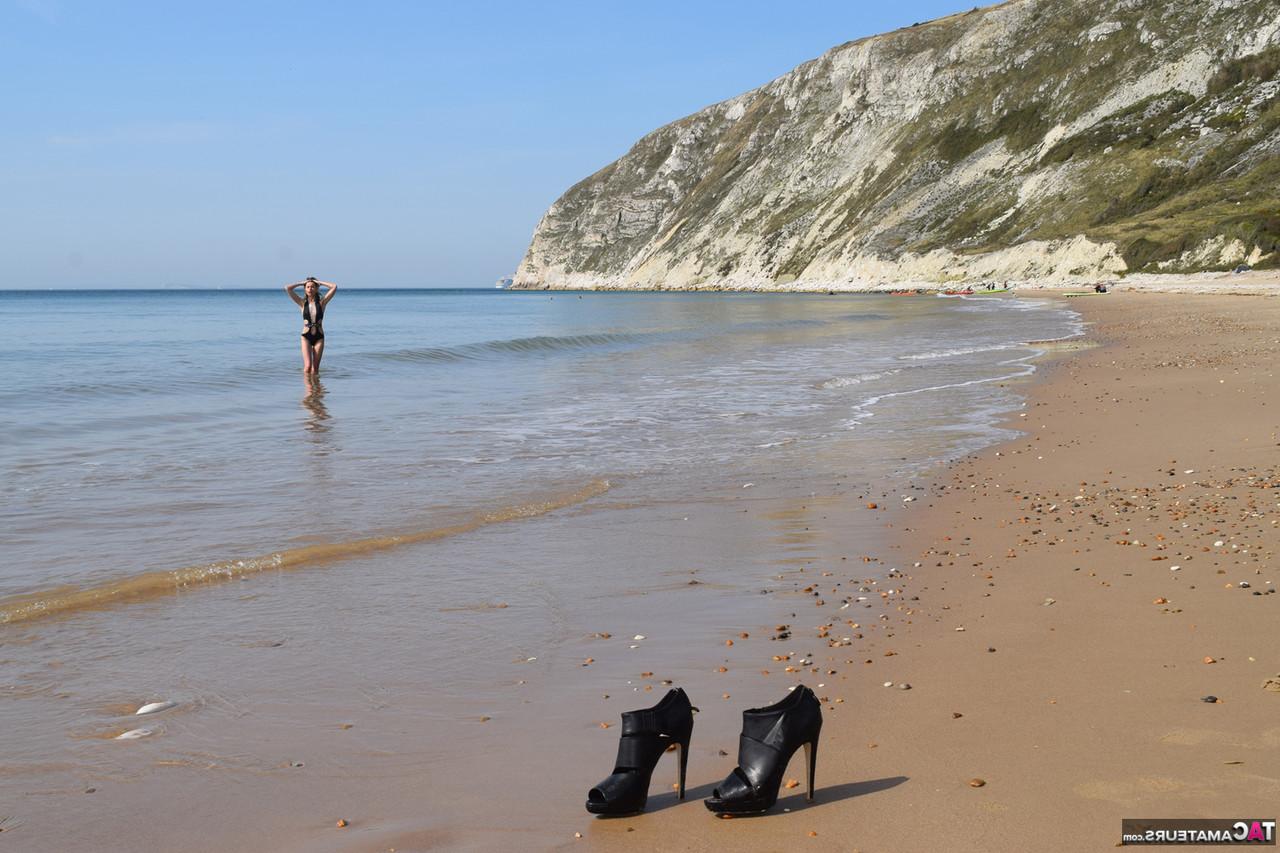20P Schlankes Mädchen lässt ihre High Heels und ihren Badeanzug am Strand zurück, um nackt ins Meer zu gehen