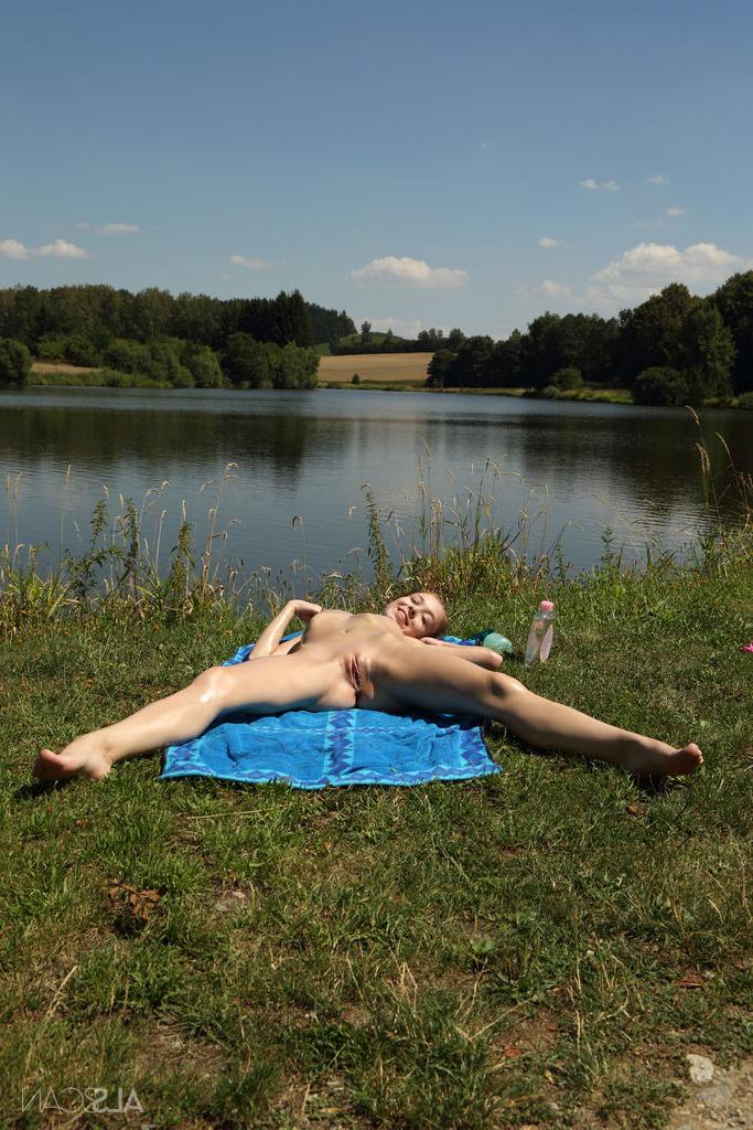 16P Une petite adolescente attache sa chatte rose alors qu'elle est nue sur une serviette au bord d'une rivière.
