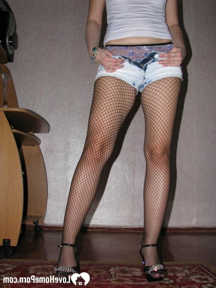20P Morena amadora posando com meia-calça arrastão e salto alto em um solo
