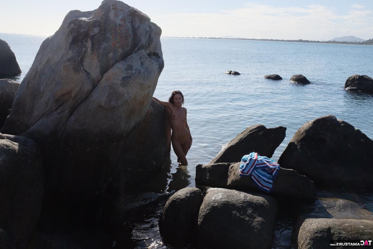 16P Die brünette MILF Roxeanne zieht sich am Strand mit Sonnenbrille aus