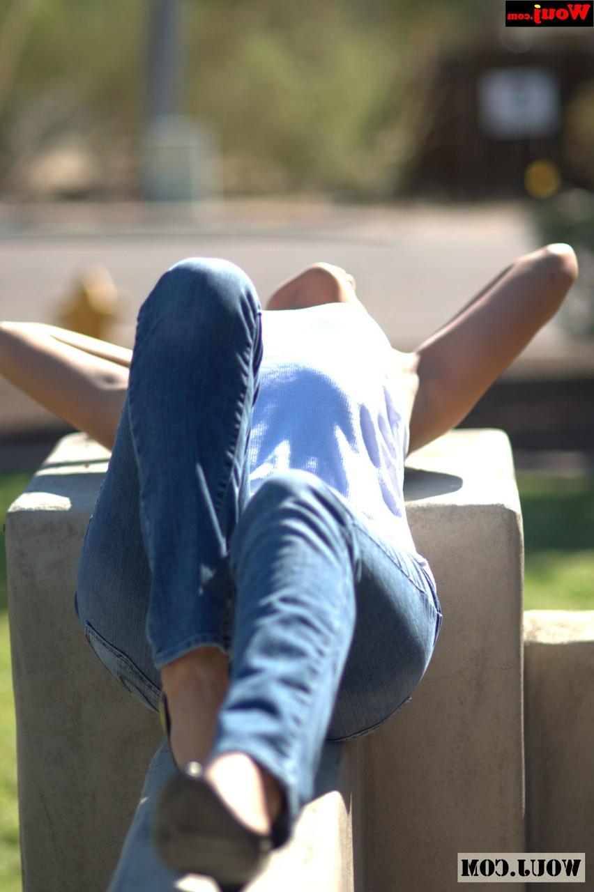 15P Gata amadora bronzeada posando com camisa branca e jeans azul em público