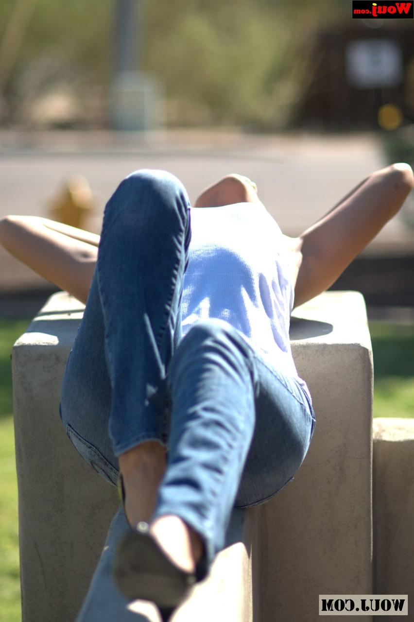 15P Gata amadora bronzeada posando com camisa branca e jeans azul em público