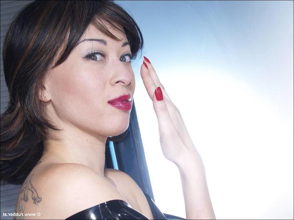 16P Bonita morena luce lápiz labial mientras fuma en ropa de látex