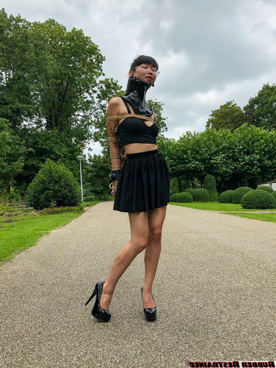 16P La asiática Flawless Meow lleva un collar con los brazos atados en un parque