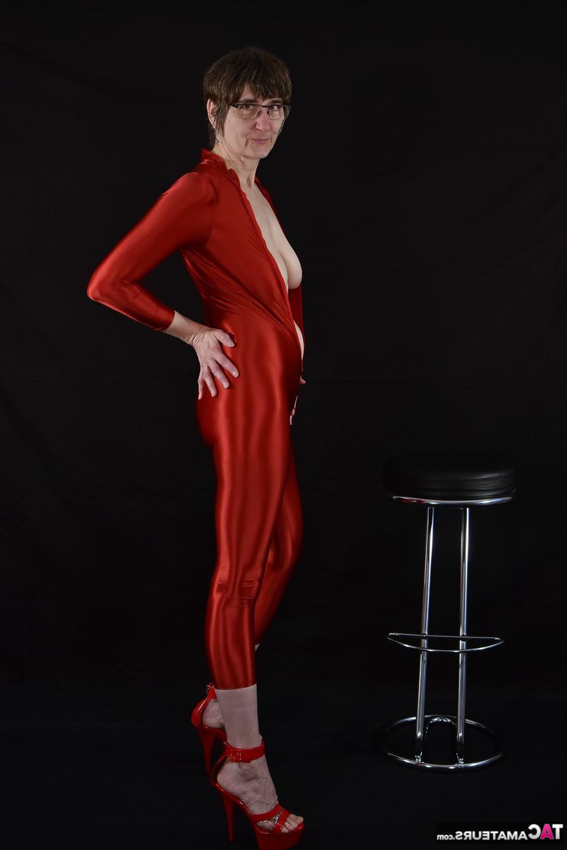 16P Brunette lady Hot MILF unzips from a shiny red catsuit in glasses and heels