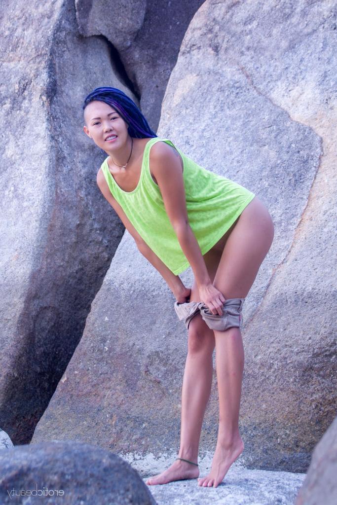 16P La joven asiática Sweet Julie se desnuda completamente en un suelo arenoso cerca de rocas