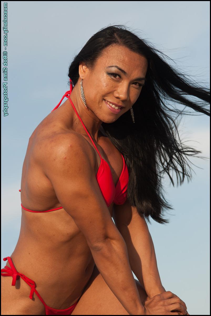 15P Tram Nguyen, mannequin asiatique de fitness, fait preuve de muscles sur une plage dans un bikini rouge.