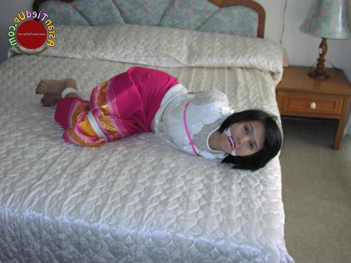 16P アジアの女の子が服を着たままベッドに縛られながら猿轡をかまされる