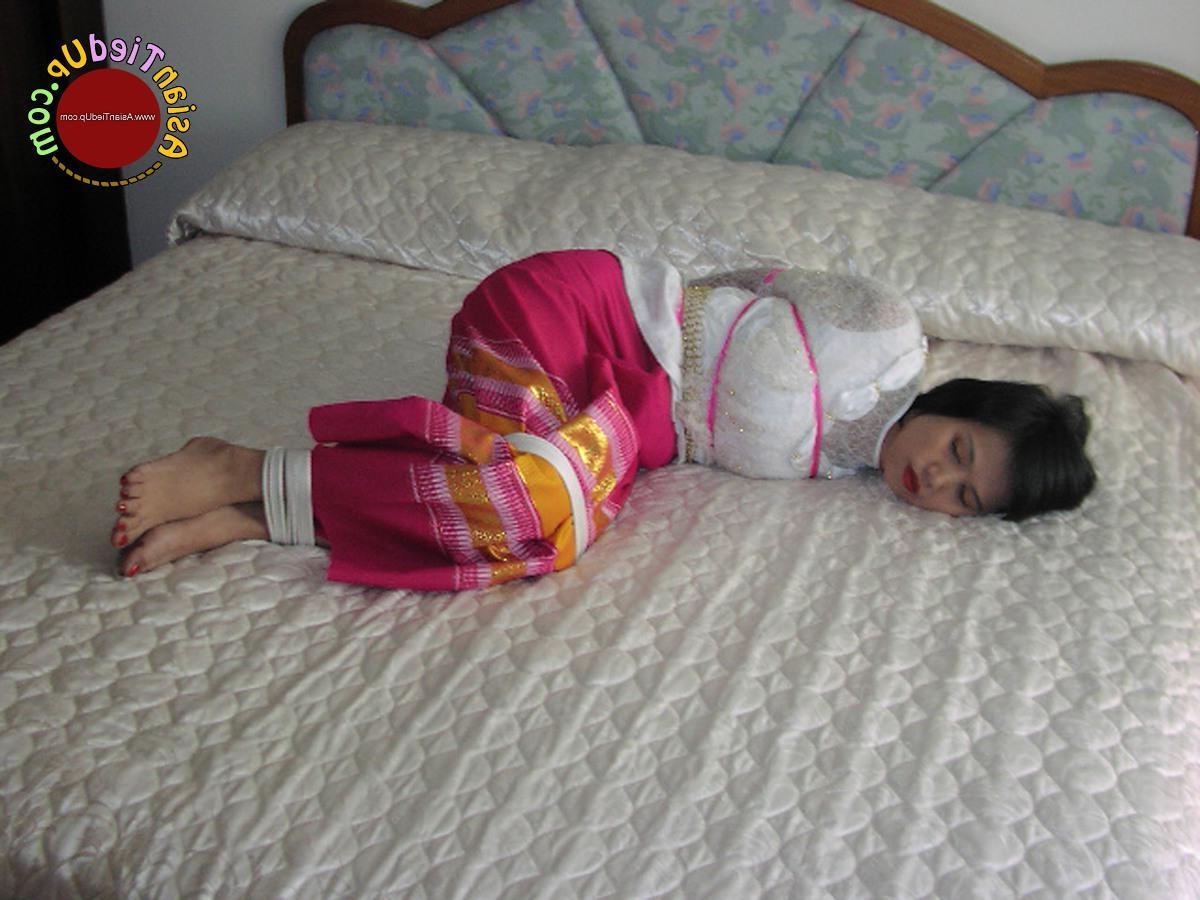 16P アジアの女の子が服を着たままベッドに縛られながら猿轡をかまされる