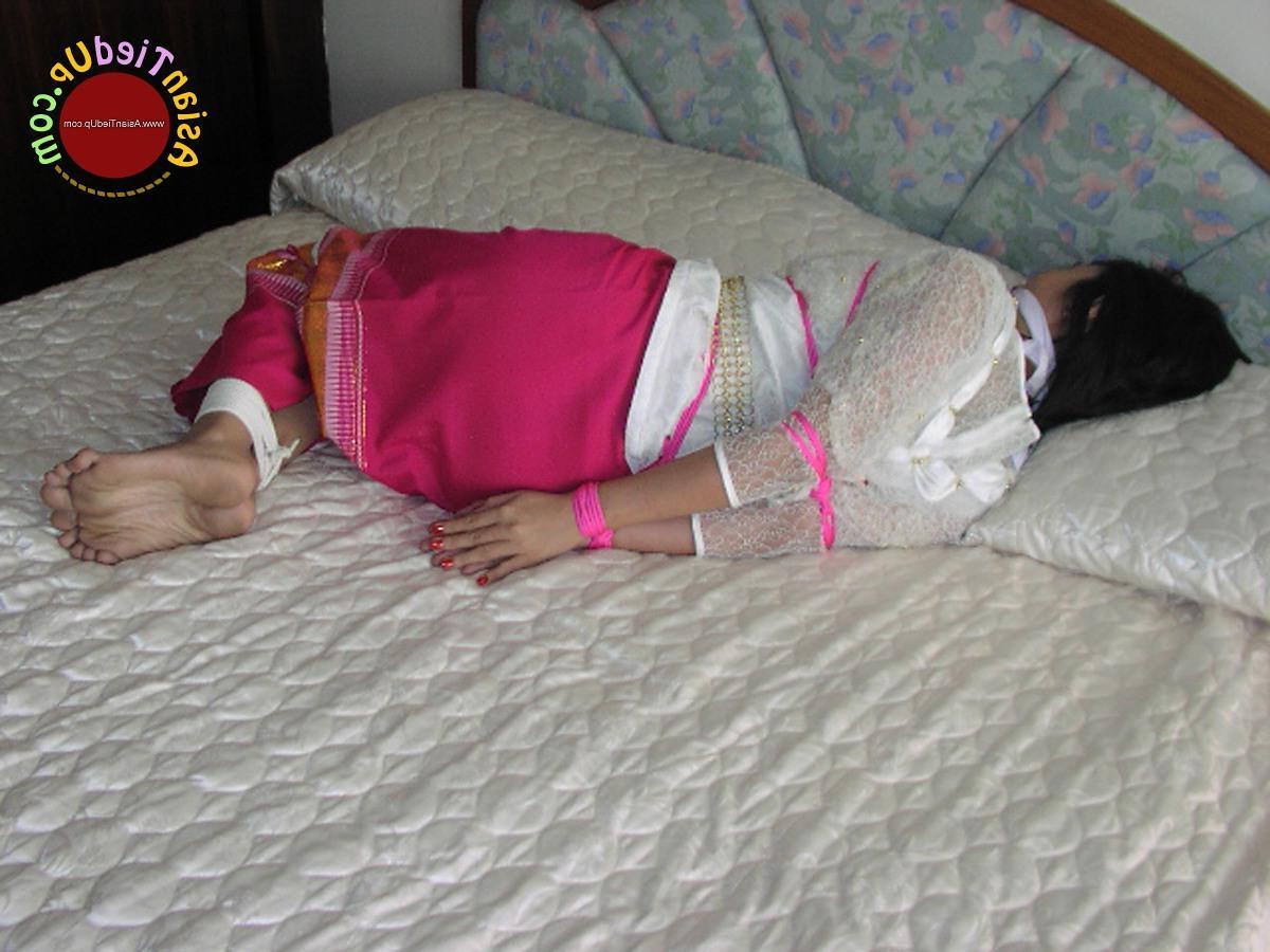 16P アジアの女の子が服を着たままベッドに縛られながら猿轡をかまされる