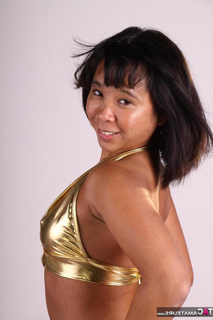20P Asiática amateur juega con su cabello mientras modela un traje dorado