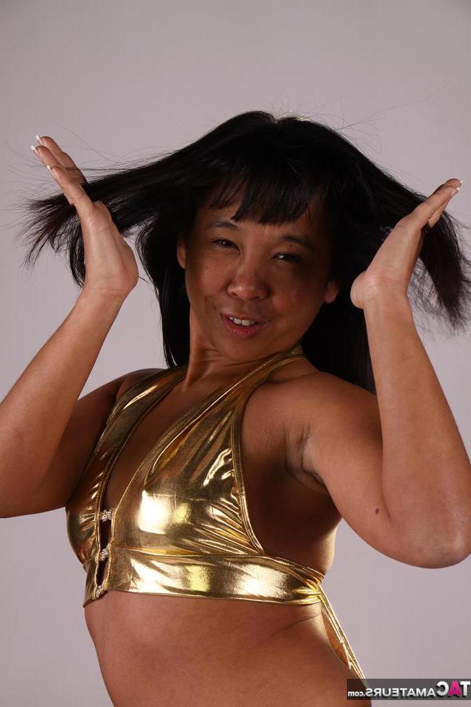 20P Asiática amateur juega con su cabello mientras modela un traje dorado