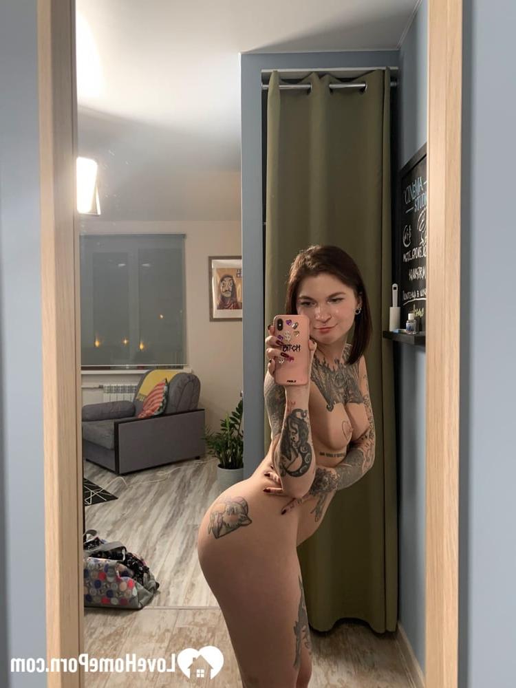 20P Une brune enjouée montre son corps tatoué en posant devant le miroir.