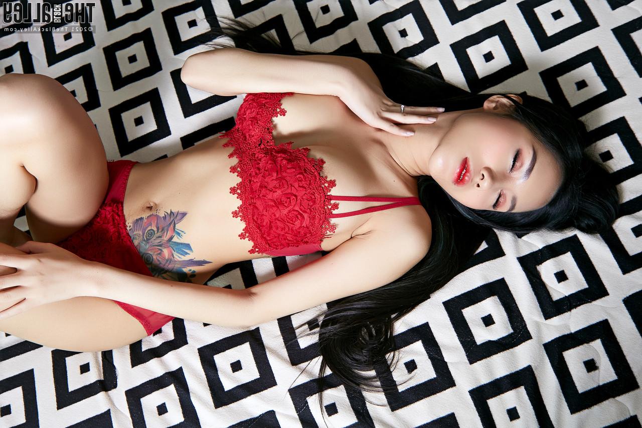 16P Die wunderschöne Asiatin Evelynne legt ihre roten Dessous aus, um sich auf einem Bett auszuziehen