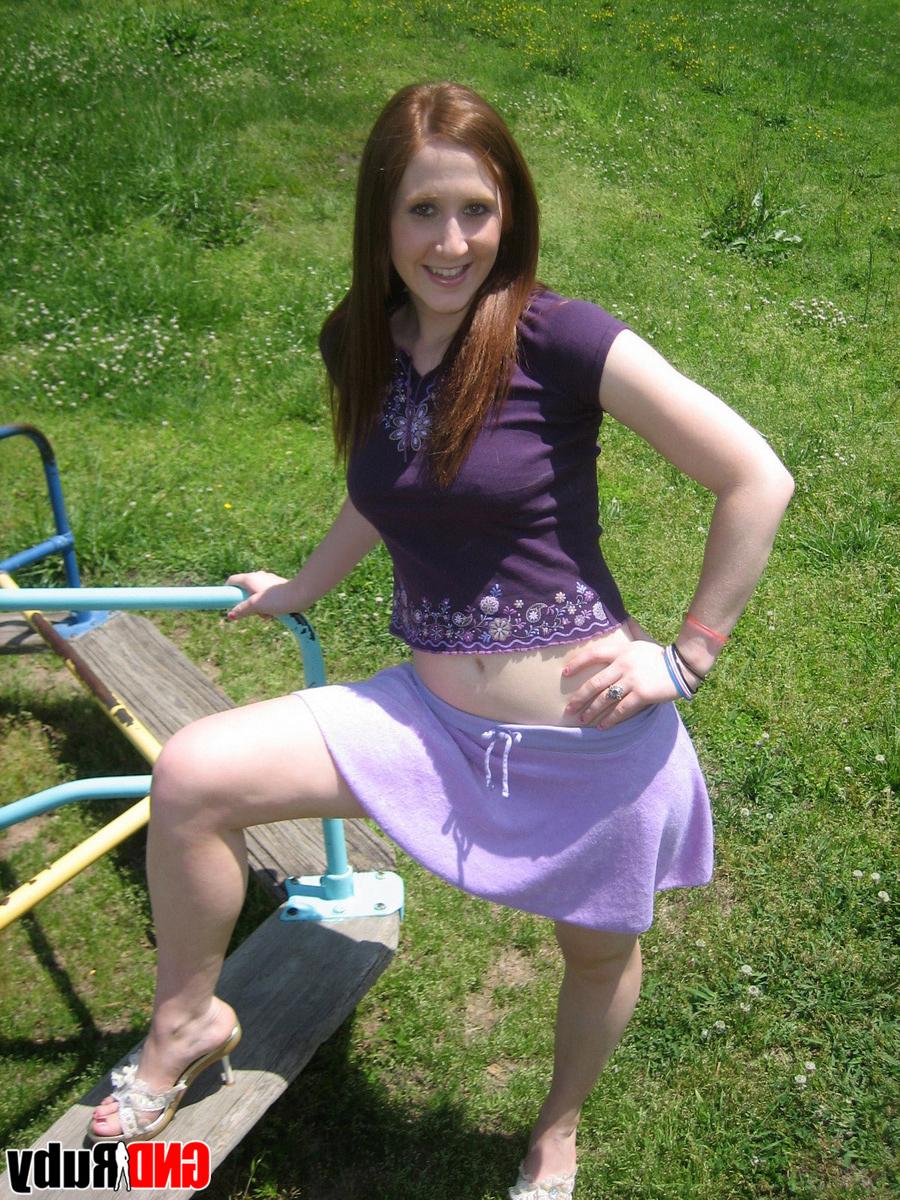12P Une jeune rousse montre ses seins et sa culotte sur une aire de jeux