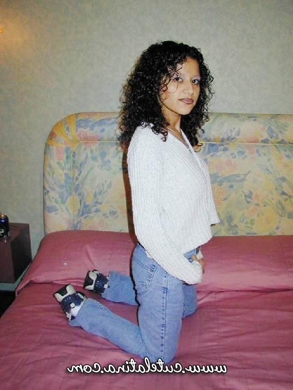 15P Une latina aux cheveux bouclés montre son cul nu sur un lit.
