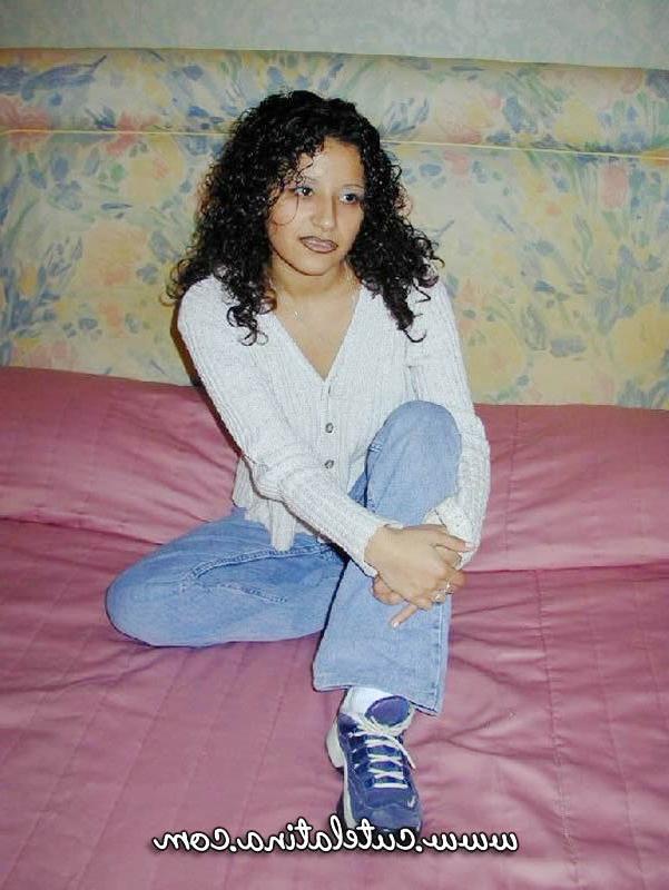 15P Une latina aux cheveux bouclés montre son cul nu sur un lit.