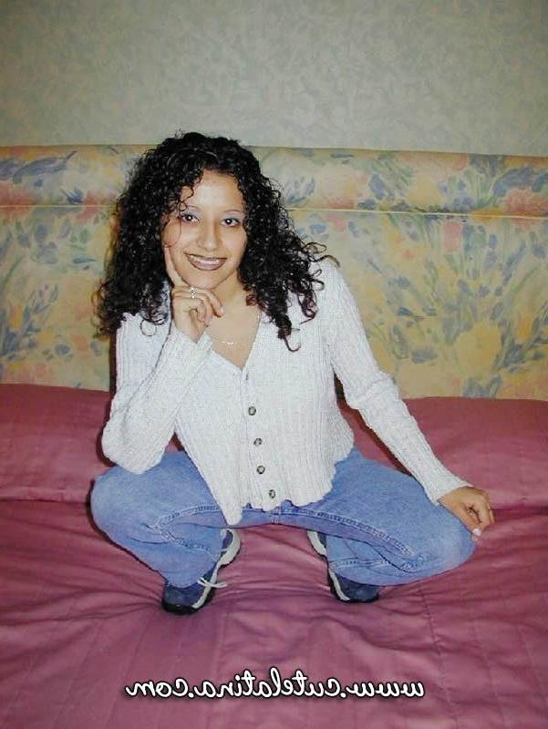 15P Une latina aux cheveux bouclés montre son cul nu sur un lit.