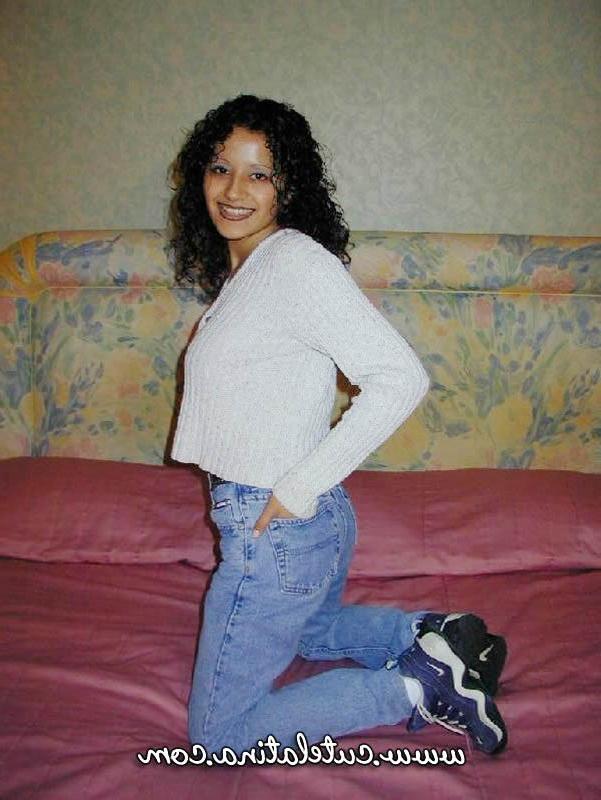 15P Une latina aux cheveux bouclés montre son cul nu sur un lit.
