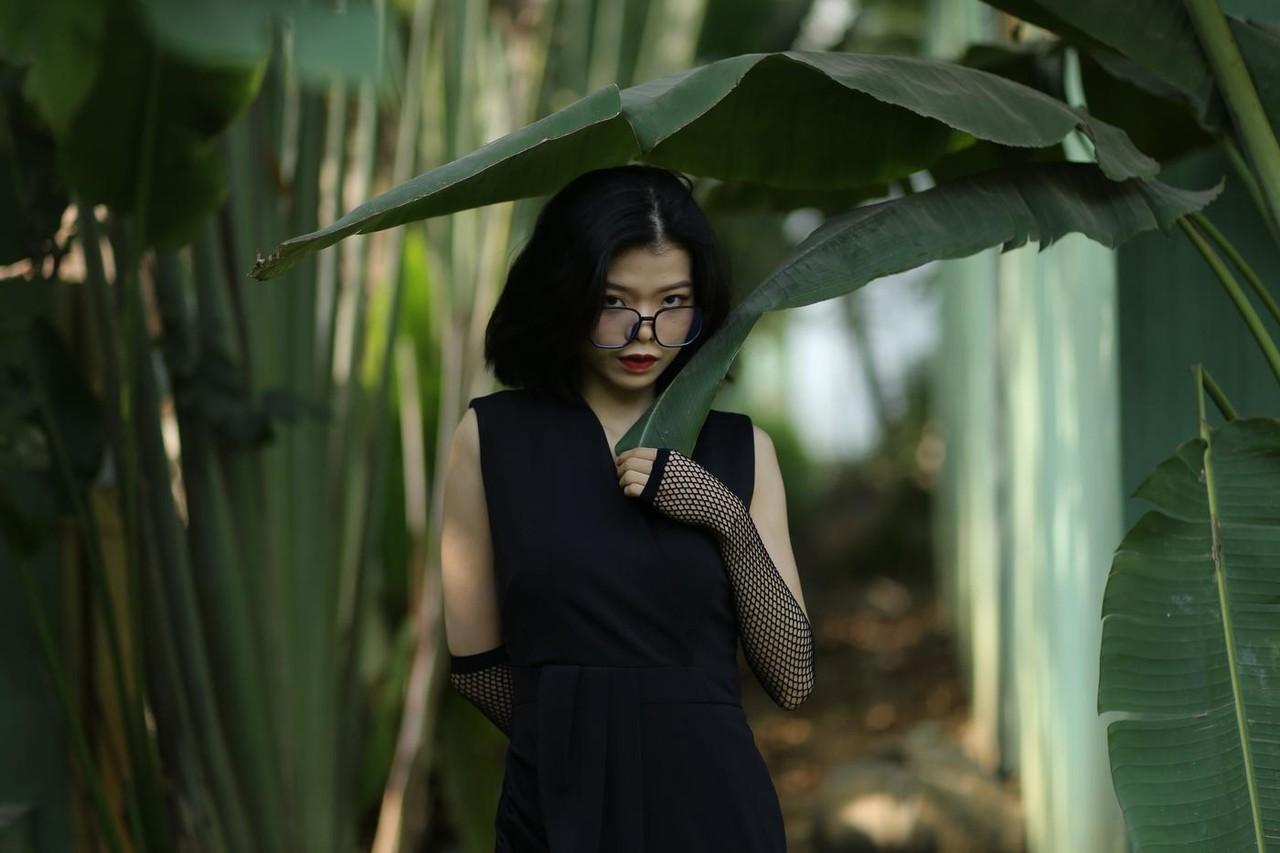 20P La pequeña asiática con gafas irena posando con su largo vestido negro al aire libre