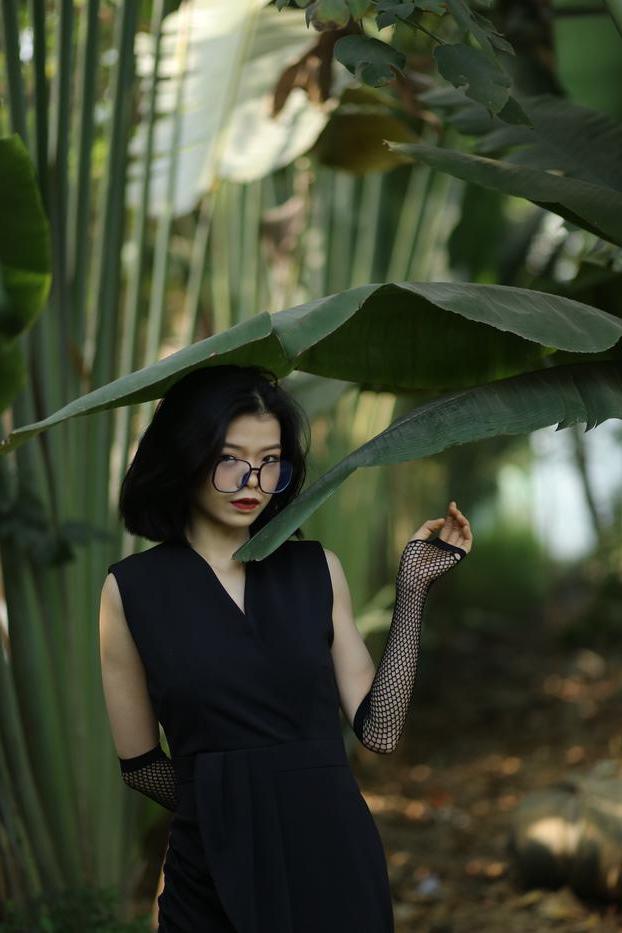 20P La pequeña asiática con gafas irena posando con su largo vestido negro al aire libre
