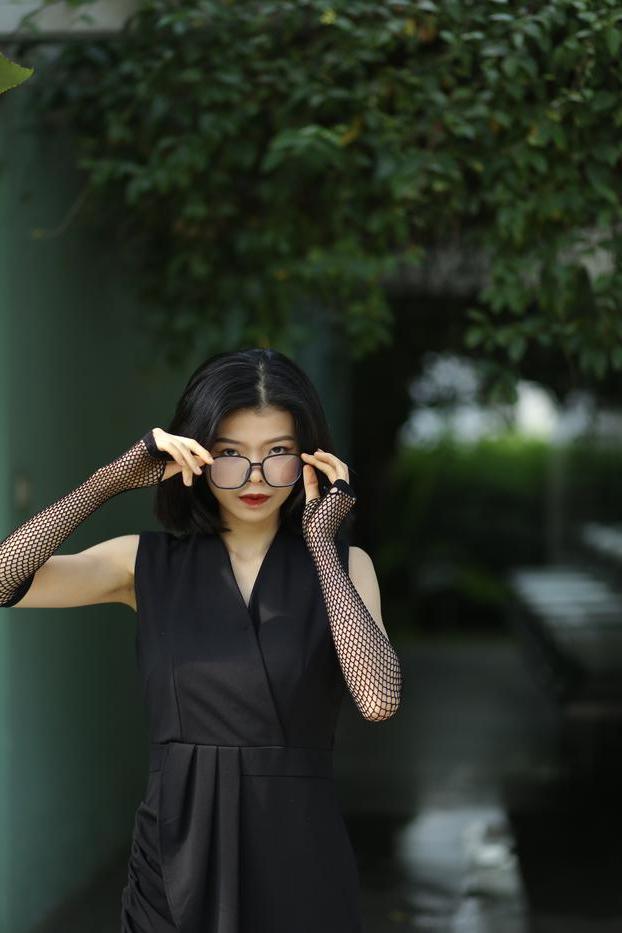 20P La pequeña asiática con gafas irena posando con su largo vestido negro al aire libre