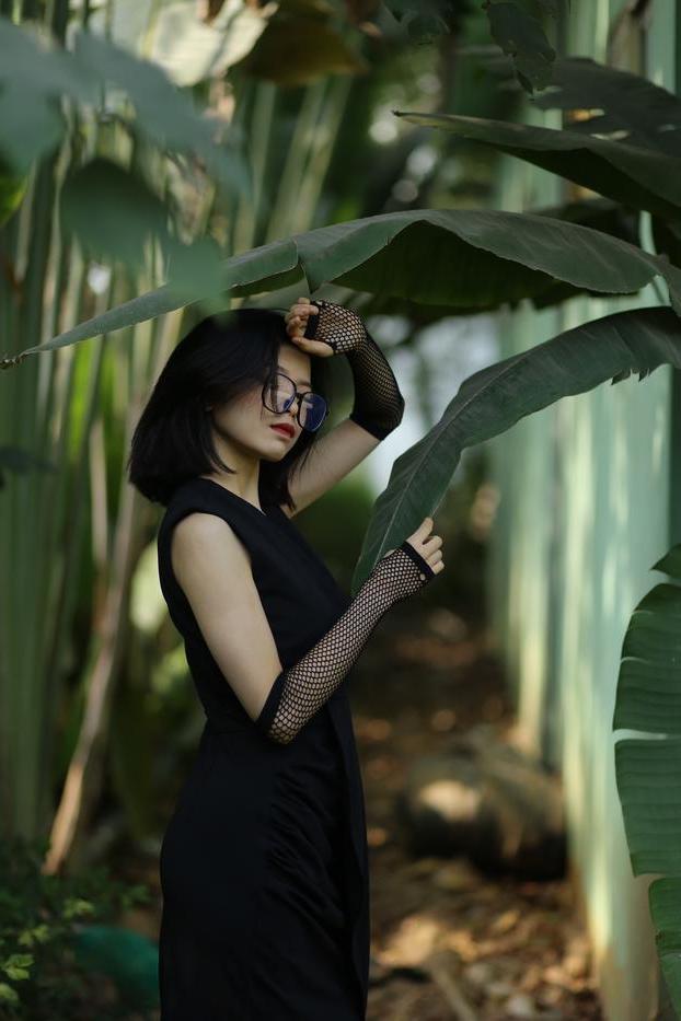 20P La pequeña asiática con gafas irena posando con su largo vestido negro al aire libre