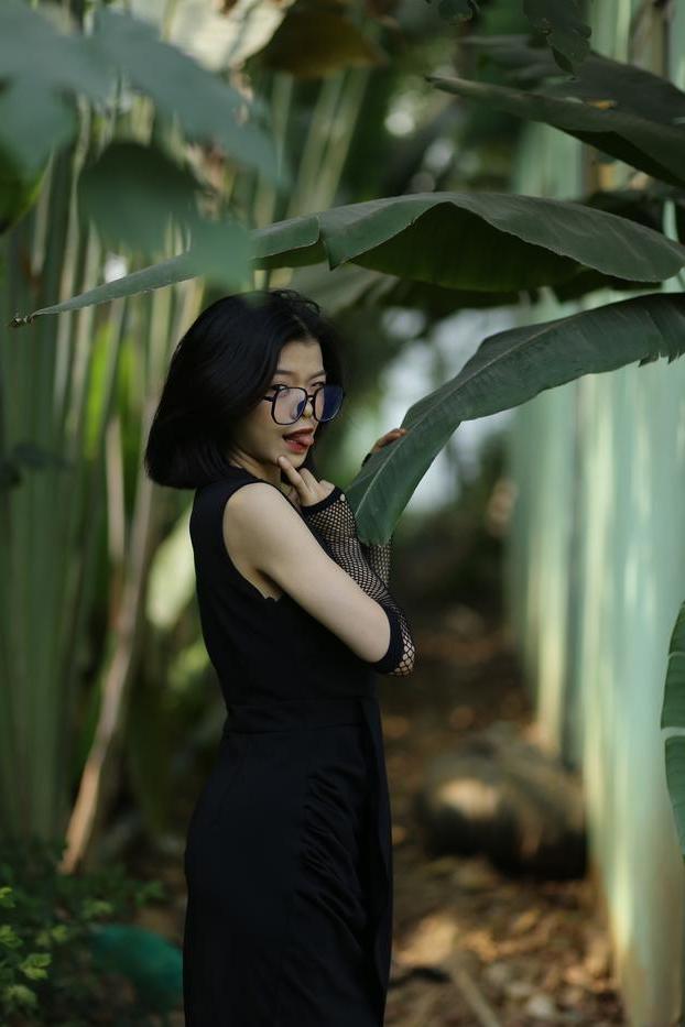 20P La pequeña asiática con gafas irena posando con su largo vestido negro al aire libre