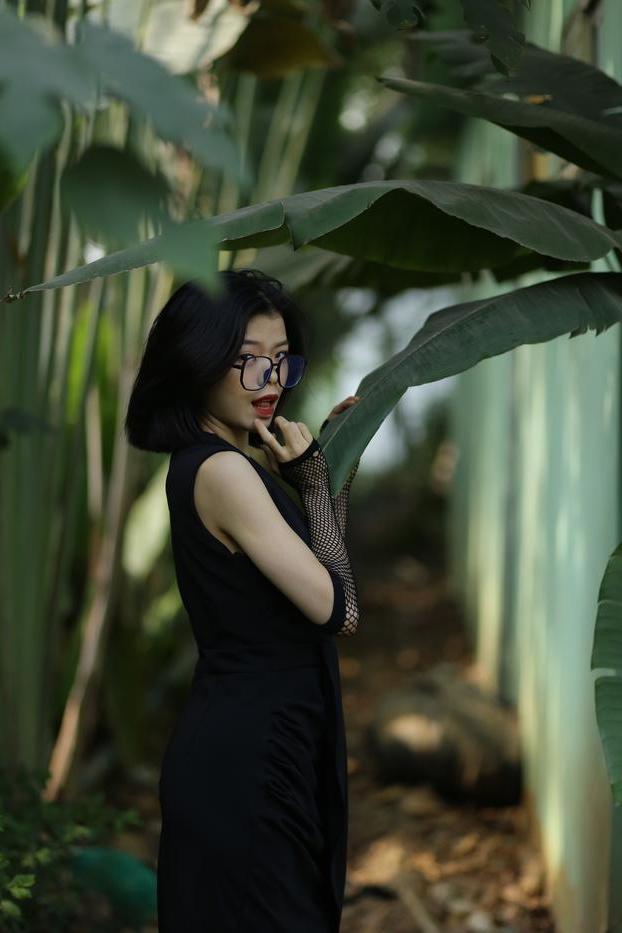 20P La pequeña asiática con gafas irena posando con su largo vestido negro al aire libre