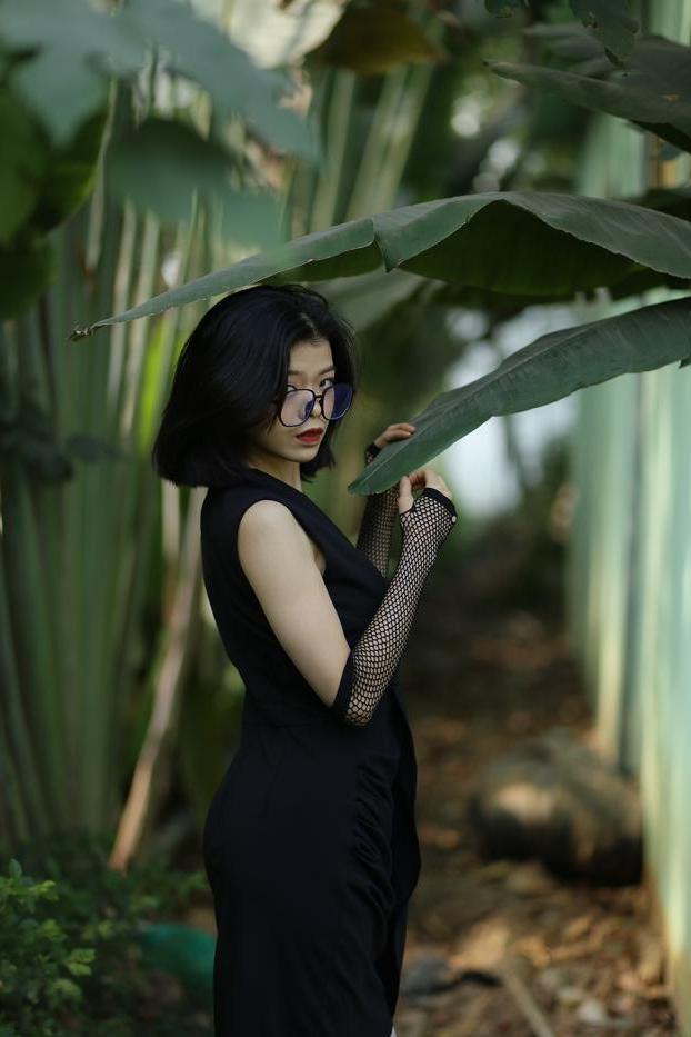 20P La pequeña asiática con gafas irena posando con su largo vestido negro al aire libre