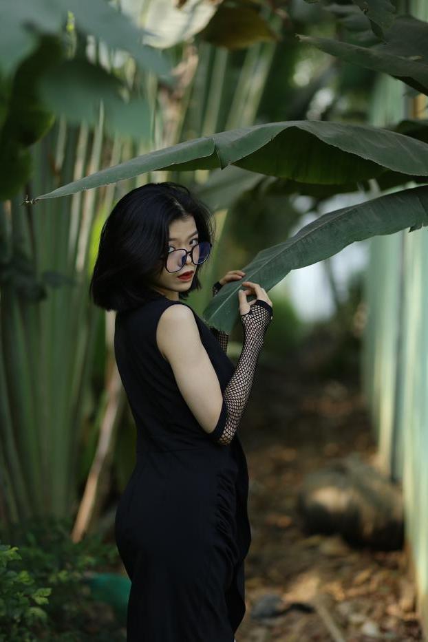 20P La pequeña asiática con gafas irena posando con su largo vestido negro al aire libre