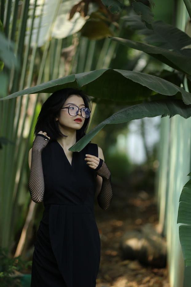 20P La pequeña asiática con gafas irena posando con su largo vestido negro al aire libre