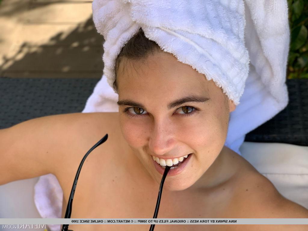 18P A jovem bela Nina Sphinx modela nua na mobília do pátio com salto vermelho