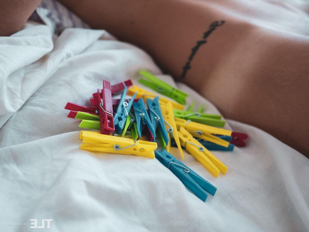 16P A adolescente nua Kerry Bradshow faz uma careta de dor enquanto prende alfinetes de roupa