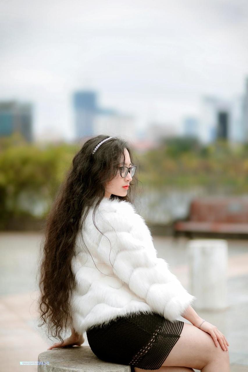 20P Jolie asiatique avec des lunettes posant dans son manteau de fourrure et sa robe en plein air