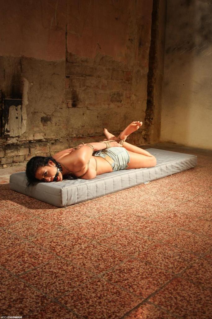 16P Topless brunette Nicole Vice struggles against rope bindings on a mattress
