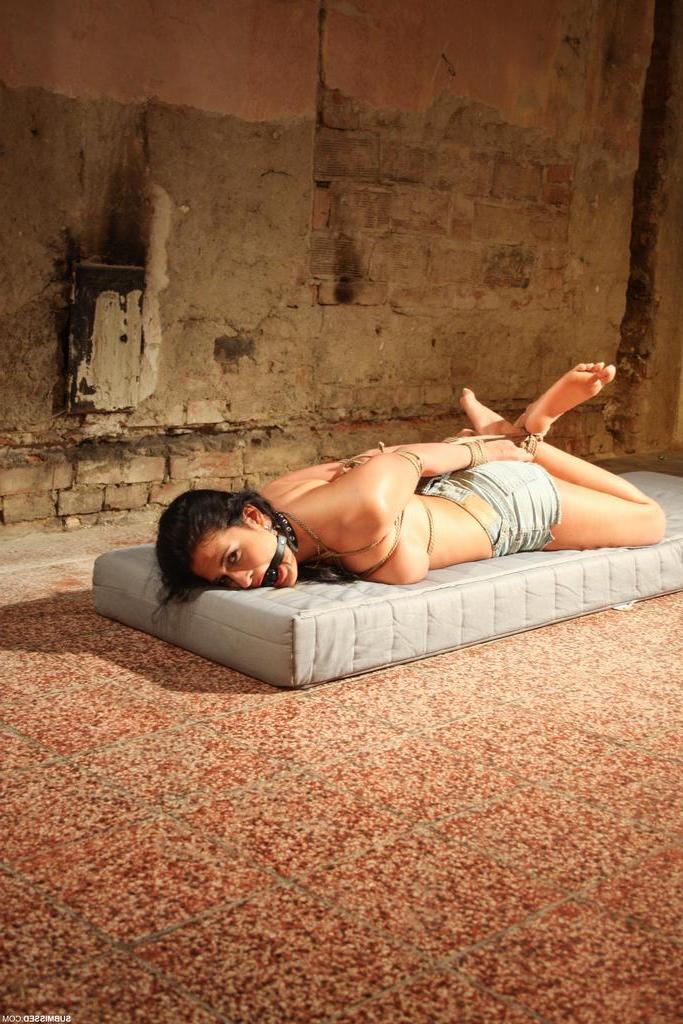 16P Topless brunette Nicole Vice struggles against rope bindings on a mattress