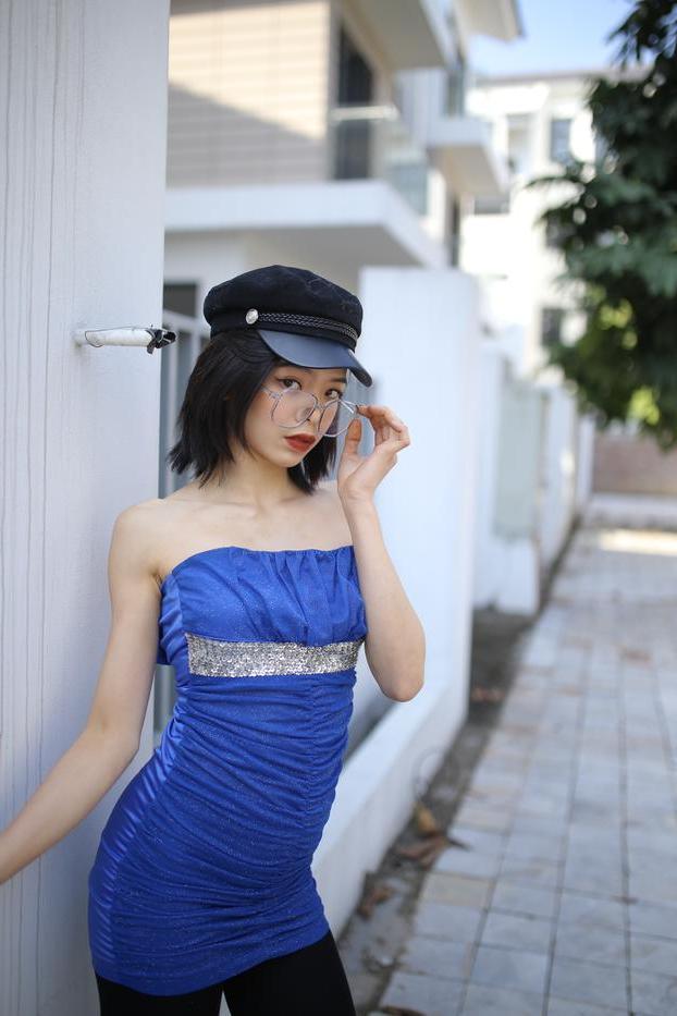 20P Bela asiática com óculos e chapéu Irena posa com seu vestido azul justo do lado de fora