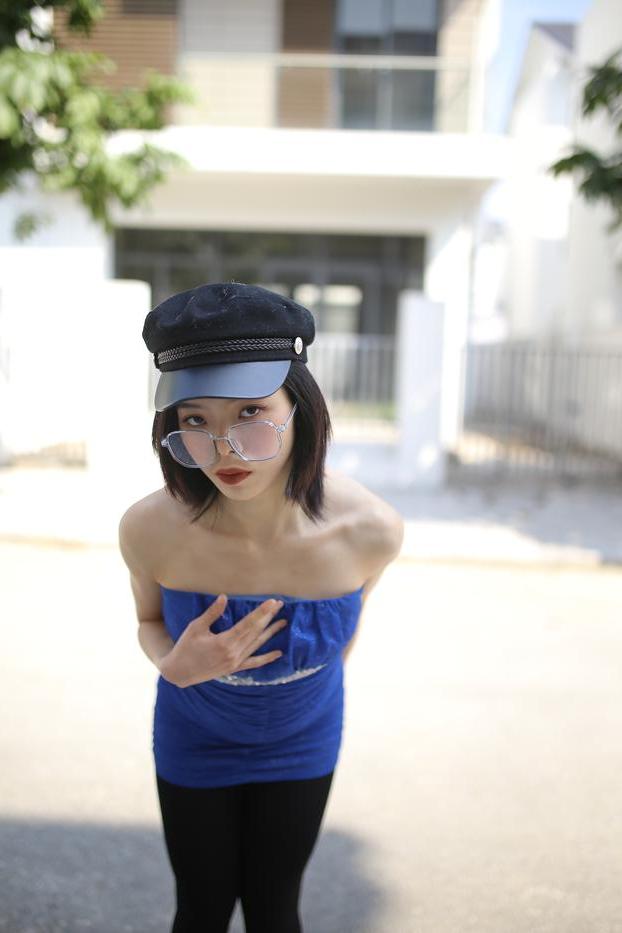 20P Bela asiática com óculos e chapéu Irena posa com seu vestido azul justo do lado de fora