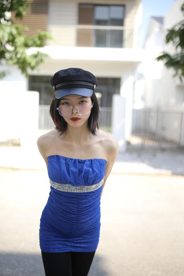 20P Bela asiática com óculos e chapéu Irena posa com seu vestido azul justo do lado de fora