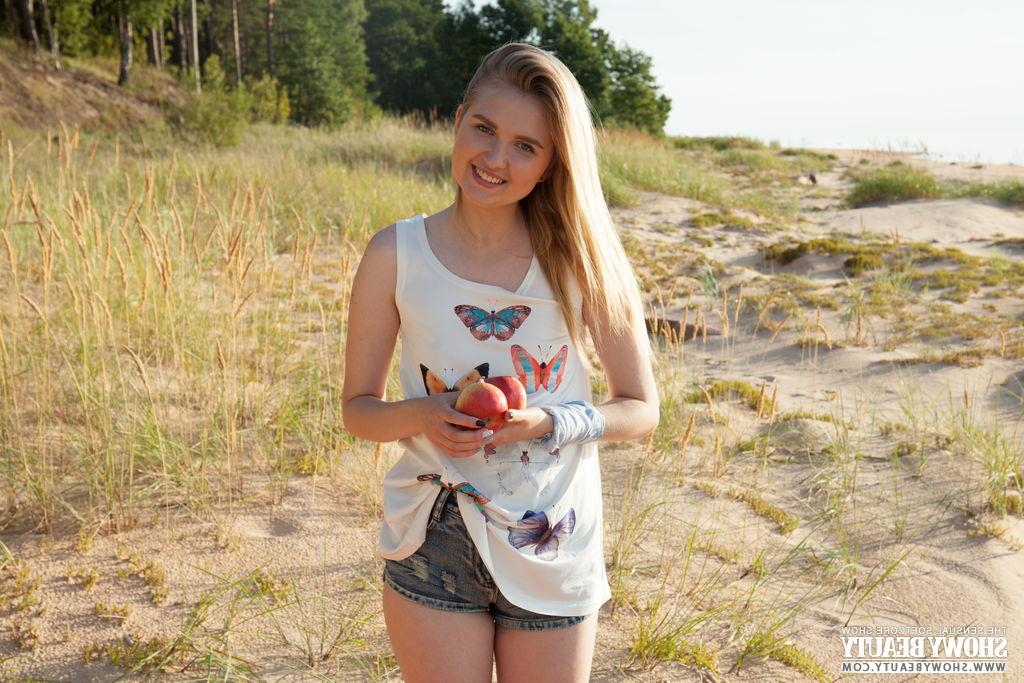20P Nimfa, petite jeune blonde, montre sa fente serrée sur une plage.