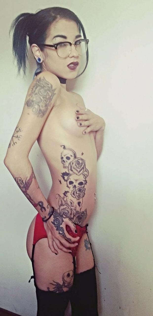 15P Das dünne Amateur-Babe Reign Rae stellt ihren tätowierten Körper zur Schau, während sie oben ohne posiert