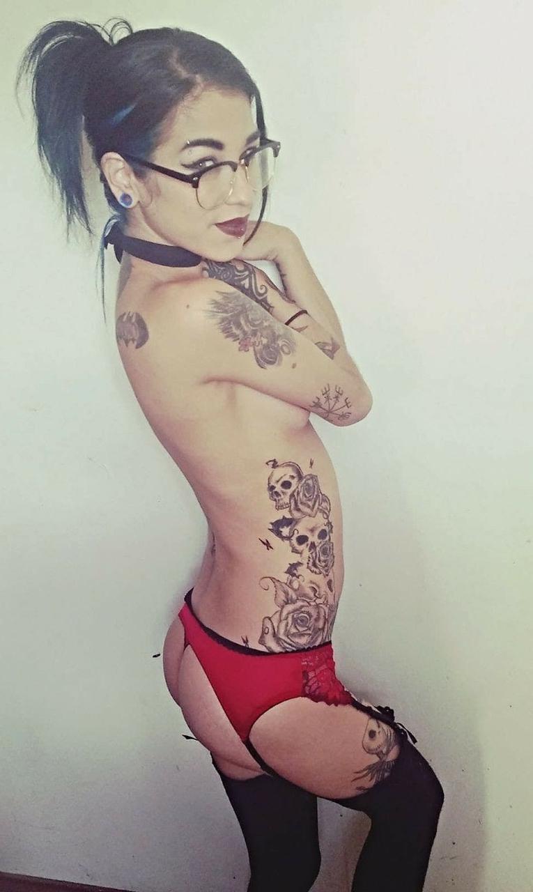 15P Das dünne Amateur-Babe Reign Rae stellt ihren tätowierten Körper zur Schau, während sie oben ohne posiert