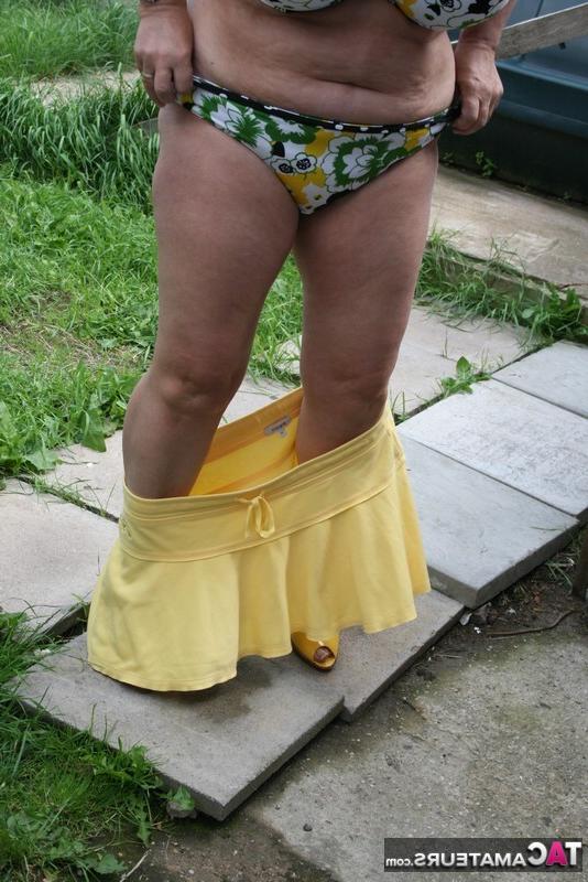 16P La gruesa mujer mayor Kinky Carol modela un bikini sobre las piedras del patio