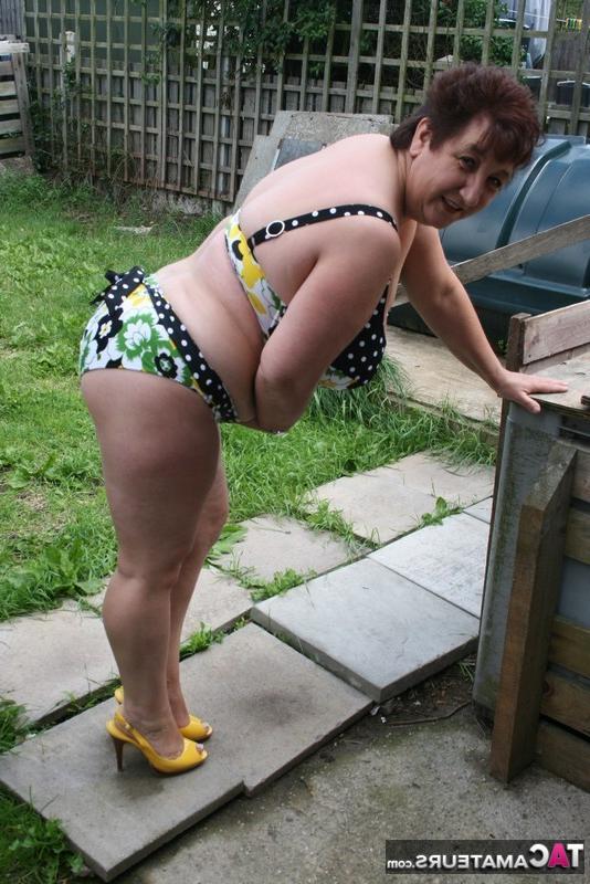 16P La gruesa mujer mayor Kinky Carol modela un bikini sobre las piedras del patio