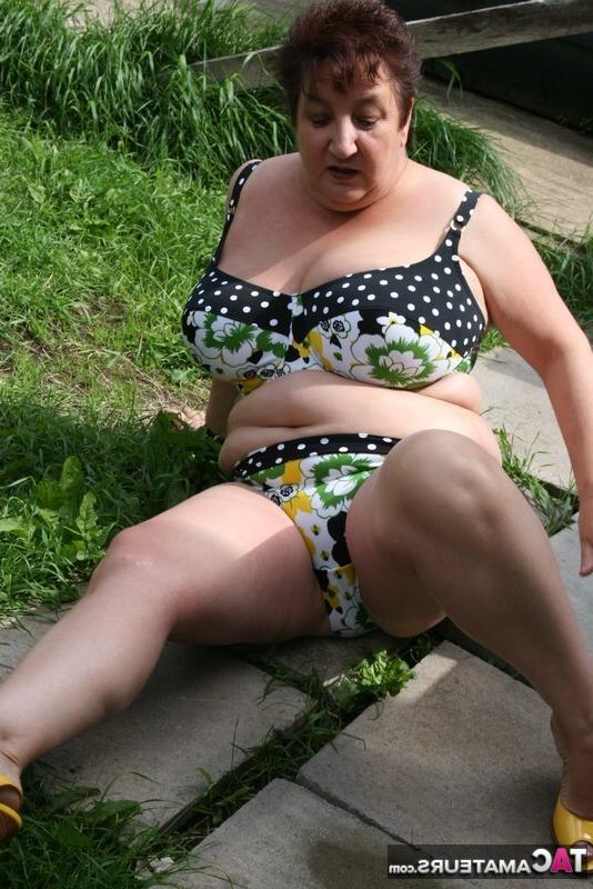 16P La gruesa mujer mayor Kinky Carol modela un bikini sobre las piedras del patio