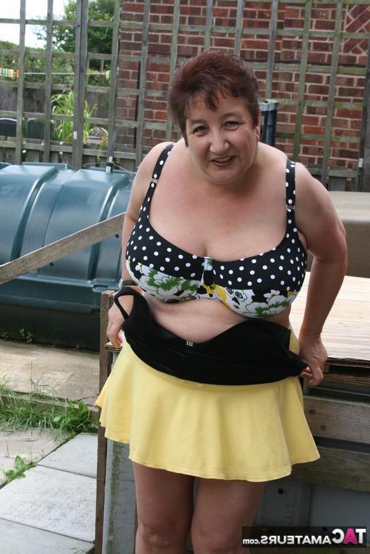 16P La gruesa mujer mayor Kinky Carol modela un bikini sobre las piedras del patio