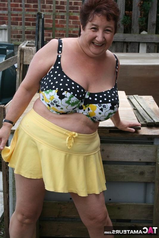 16P La gruesa mujer mayor Kinky Carol modela un bikini sobre las piedras del patio