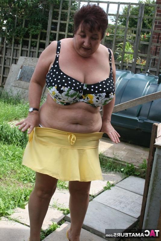 16P La gruesa mujer mayor Kinky Carol modela un bikini sobre las piedras del patio